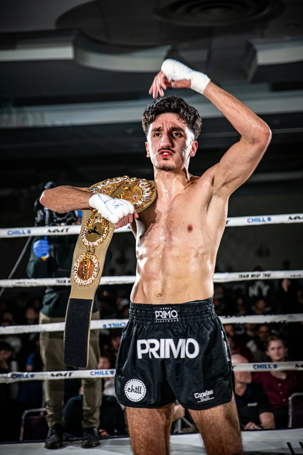 A fighter holding his title belt in the ring at MMT 9
