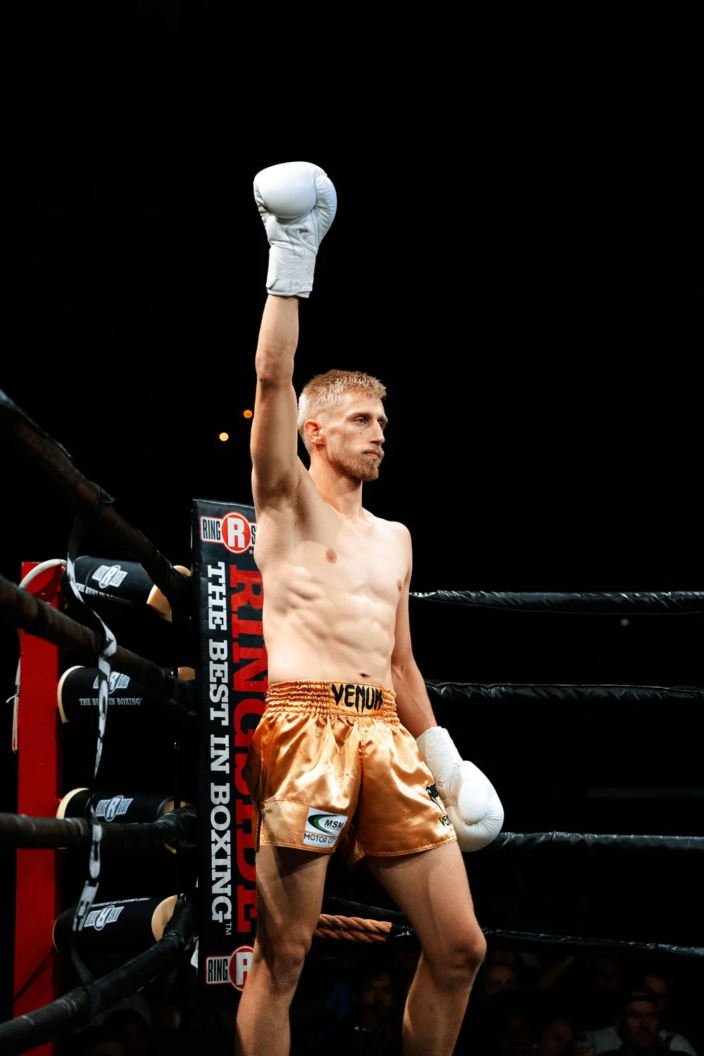 A fighter raising his glove in his corner before the bell