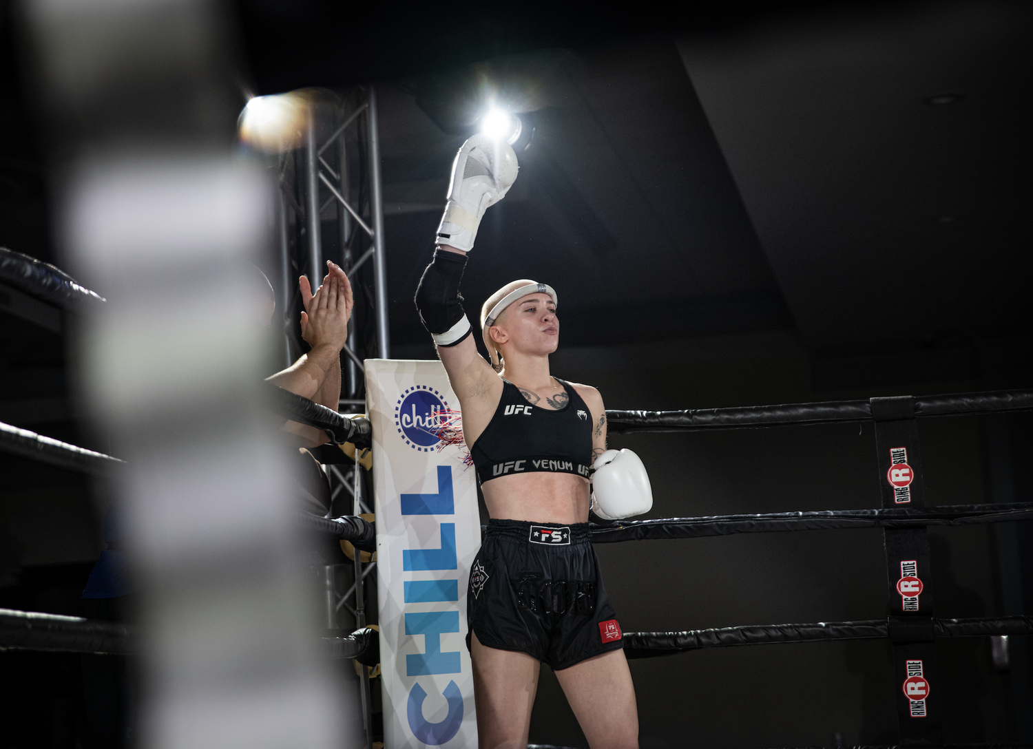 Coach McKenna Diener with her glove raised in the ring after a fight