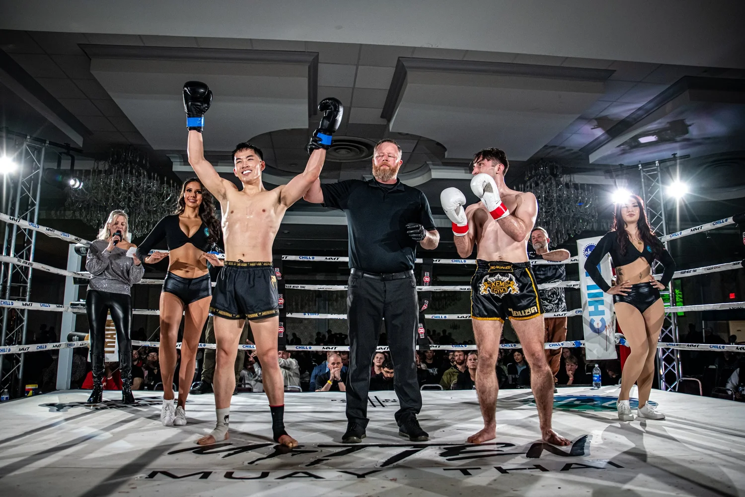 A fighter with both hands raised by the referee after winning at MMT 9