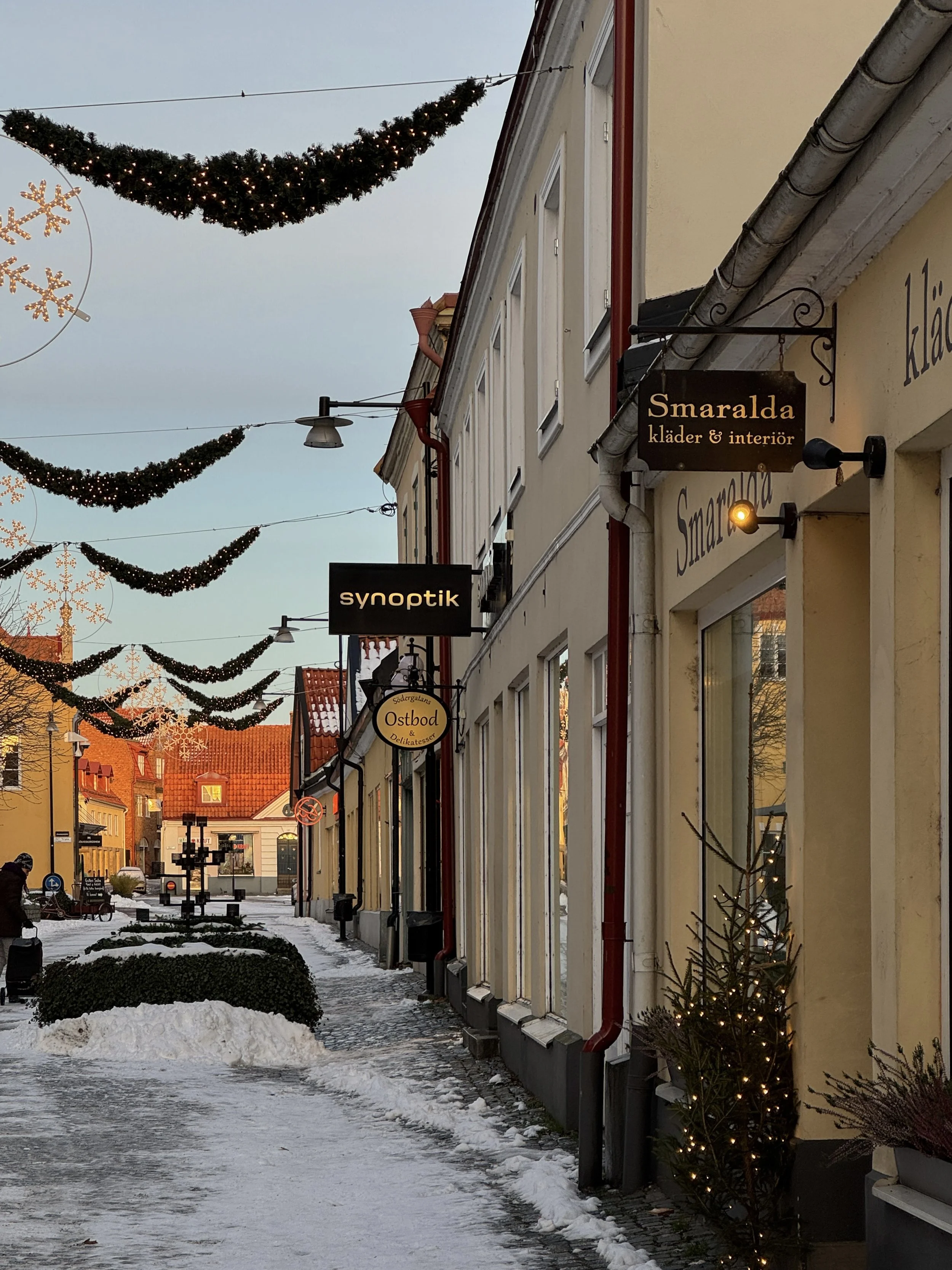 Ett bord dukat med tallrikar, ett glas, ett vattenglas, en liten skål, en ljusstake och bestick i guld. Duk, tallrikar och bestick i rosa, blå och guld, på rosa duk.