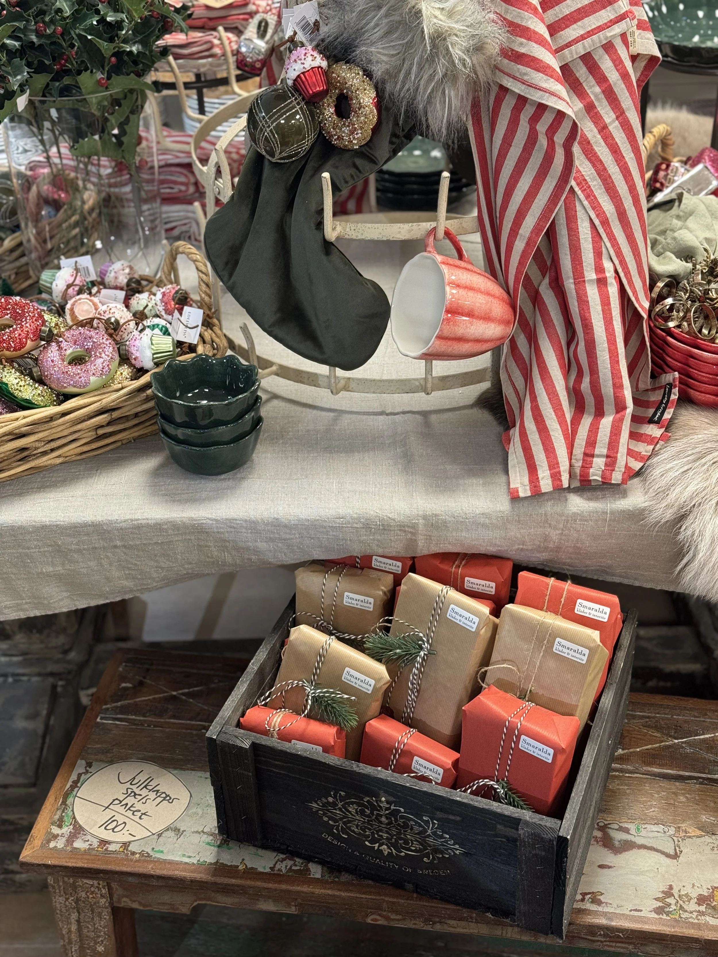 En tallrik med blå och orange blommönster, en skål och guldfärgade bestick på en rosa duk.