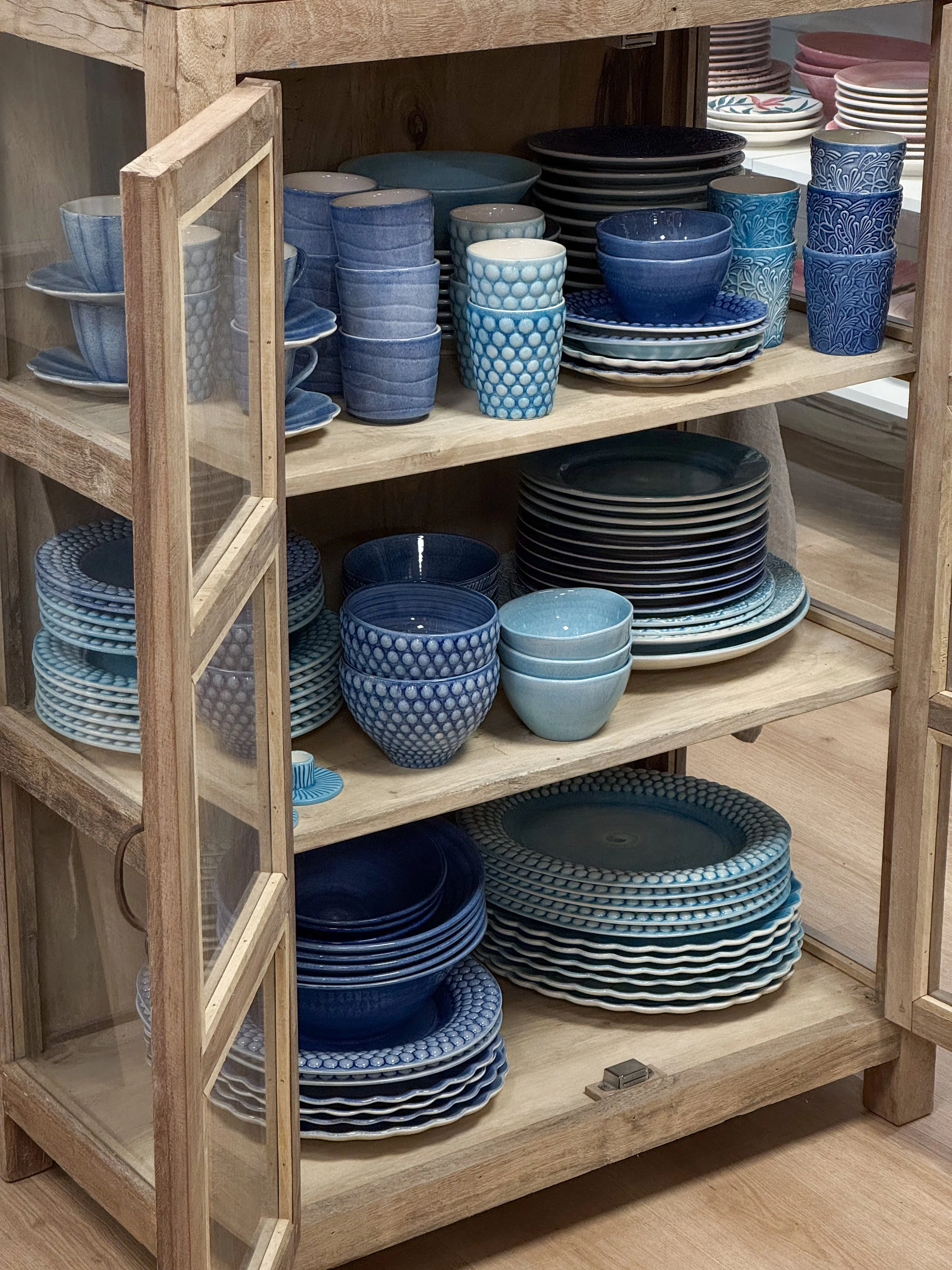 Två beanie-hattar, en olivgrön och en beige, hängande på en metallstång med prislappar.