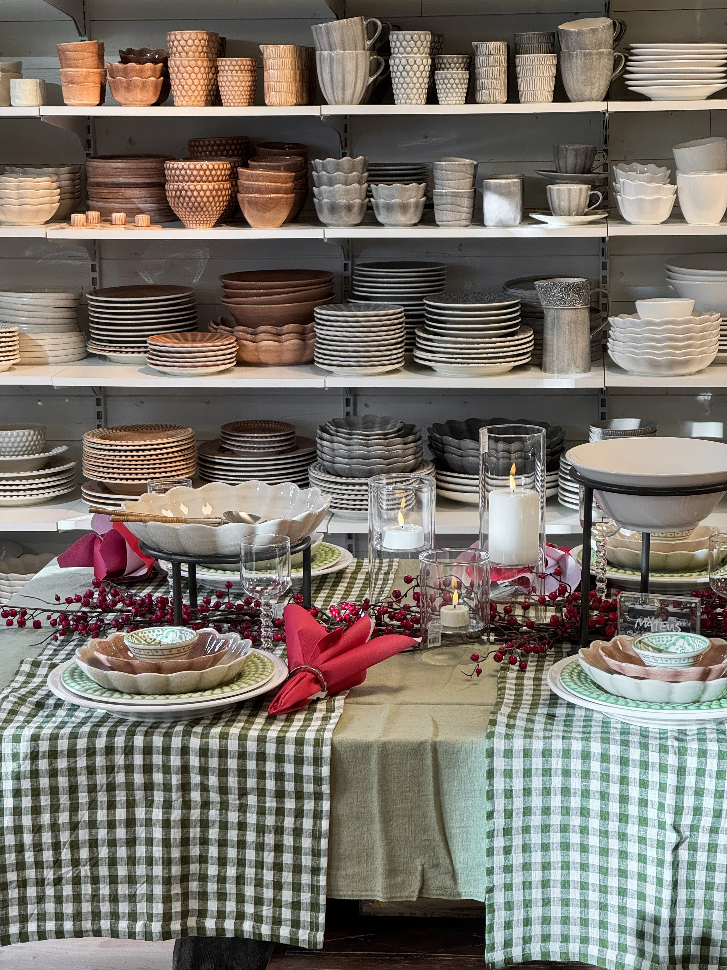 Tre stickade tröjor i vita, rosa och gråa, hängande på en metallställning.