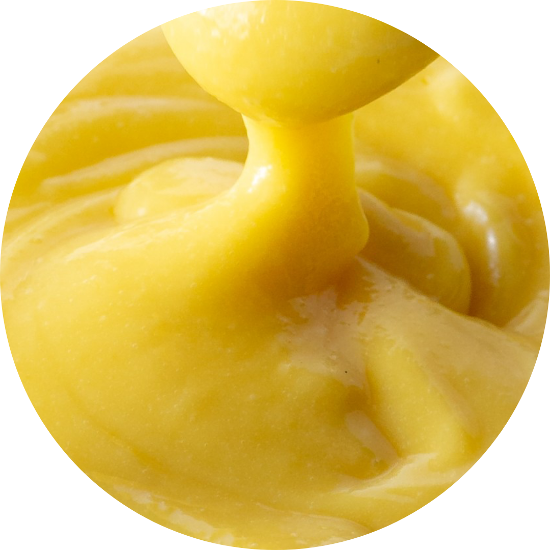 Close-up of bright yellow lemon curd being poured or spread.