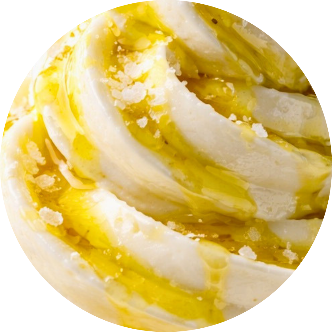 Close-up of a swirl of vanilla soft serve ice cream topped with a drizzle of honey or caramel sauce and sprinkles of crushed white topping.