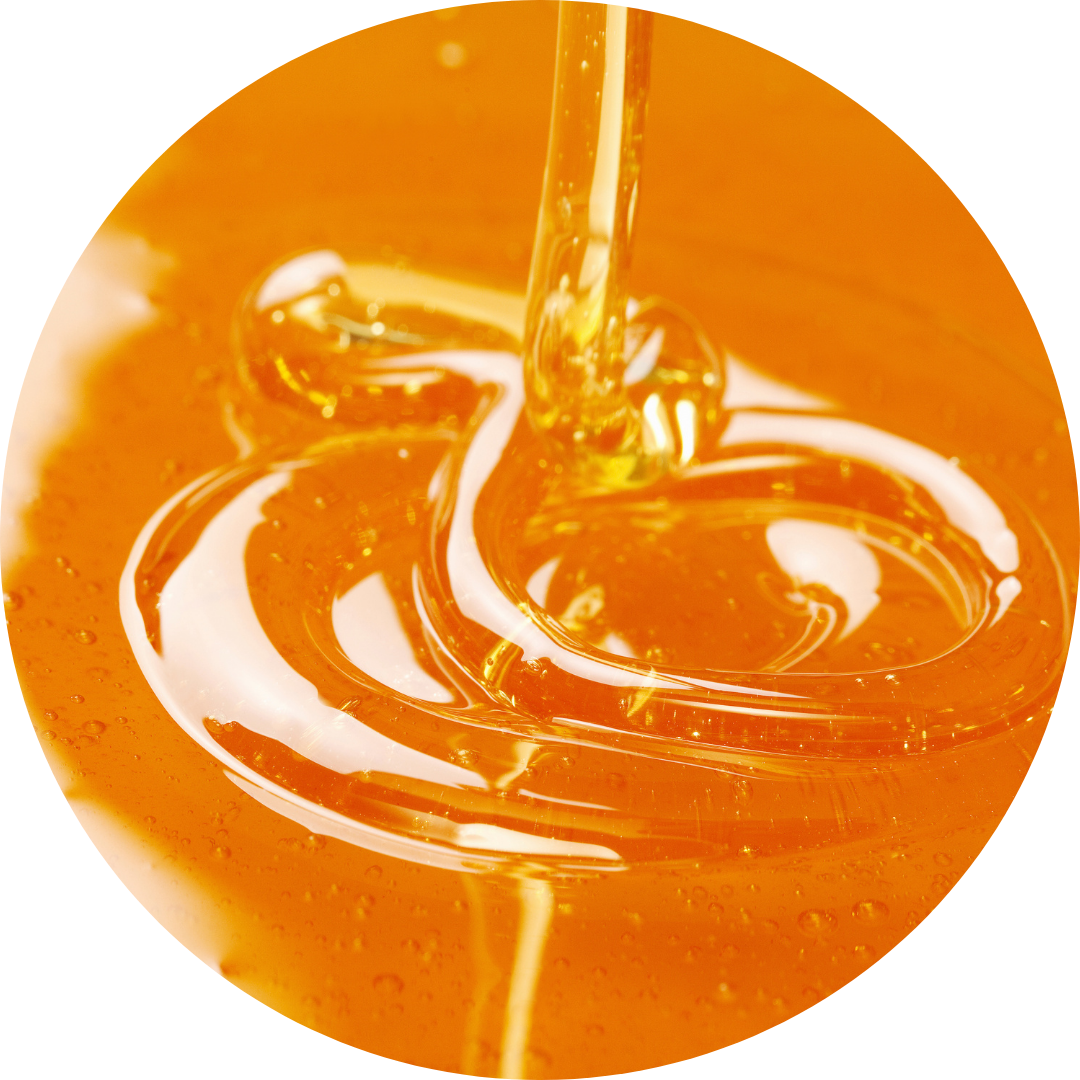 Golden honey being poured and swirling in a glass jar.