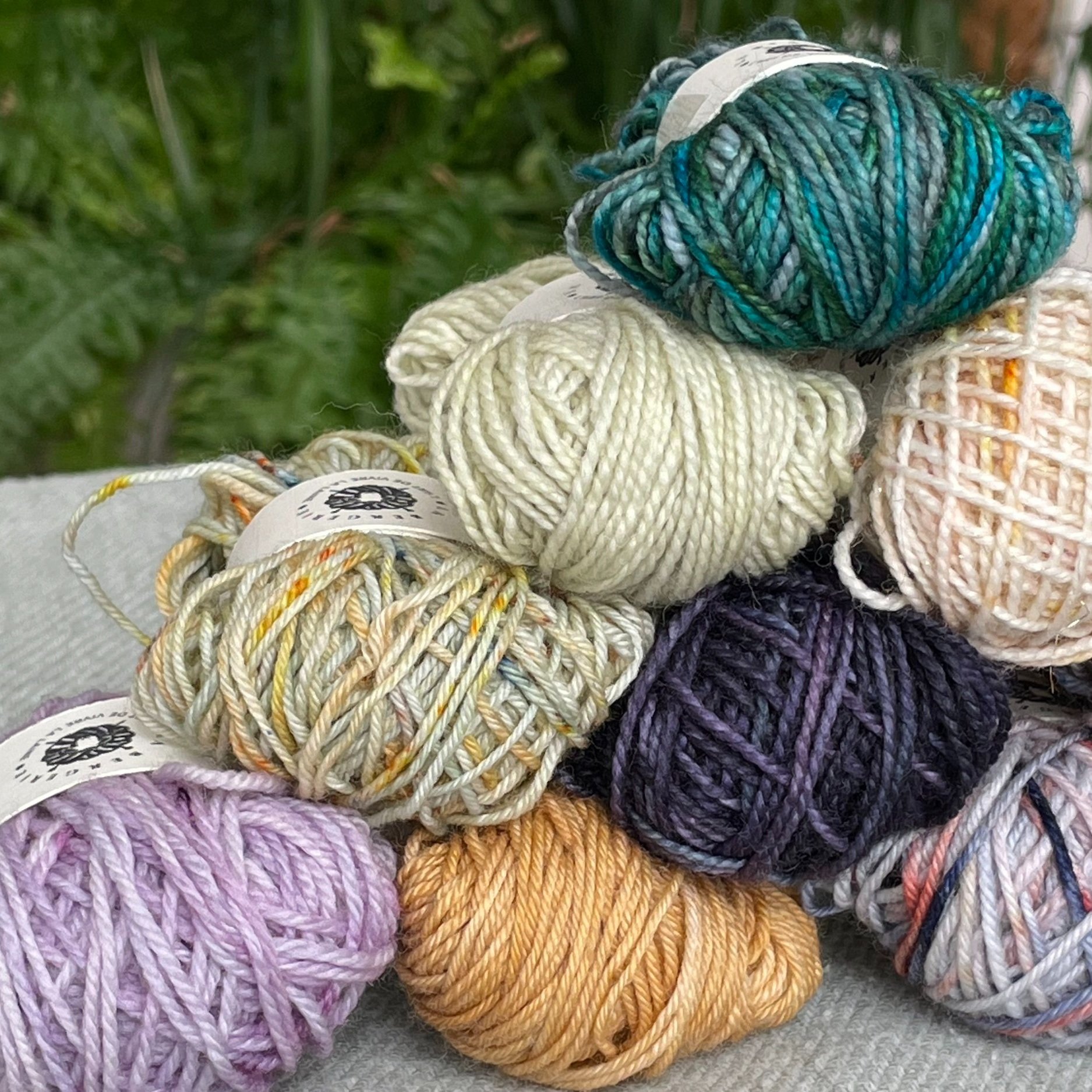 Pile de pelotons de laine artisanale dans des tons riches, exposée sur un fond naturel