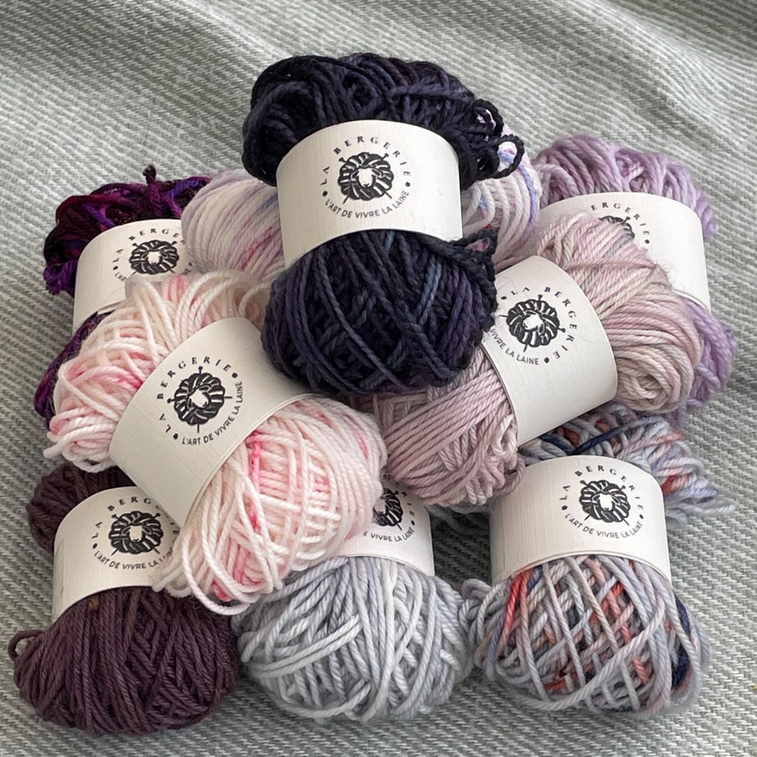 Pile de mini-pelotons de laine artisanale dans des couleurs variées, idéale pour des projets de tricot