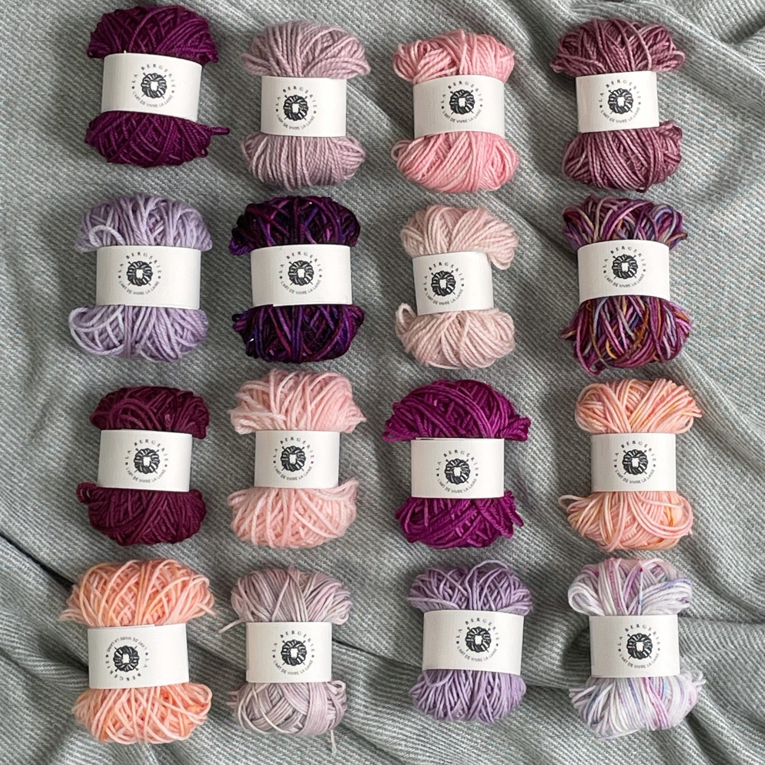 Mini-pelotons de laine artisanale dans des teintes pastel et douces, disposés sur un fond neutre