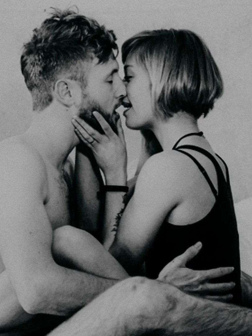 Ein Mann und eine Frau befinden sich sehr nahe beieinander, sie scheinen sich zu küssen oder zu umarmen, in einer intimen Pose.