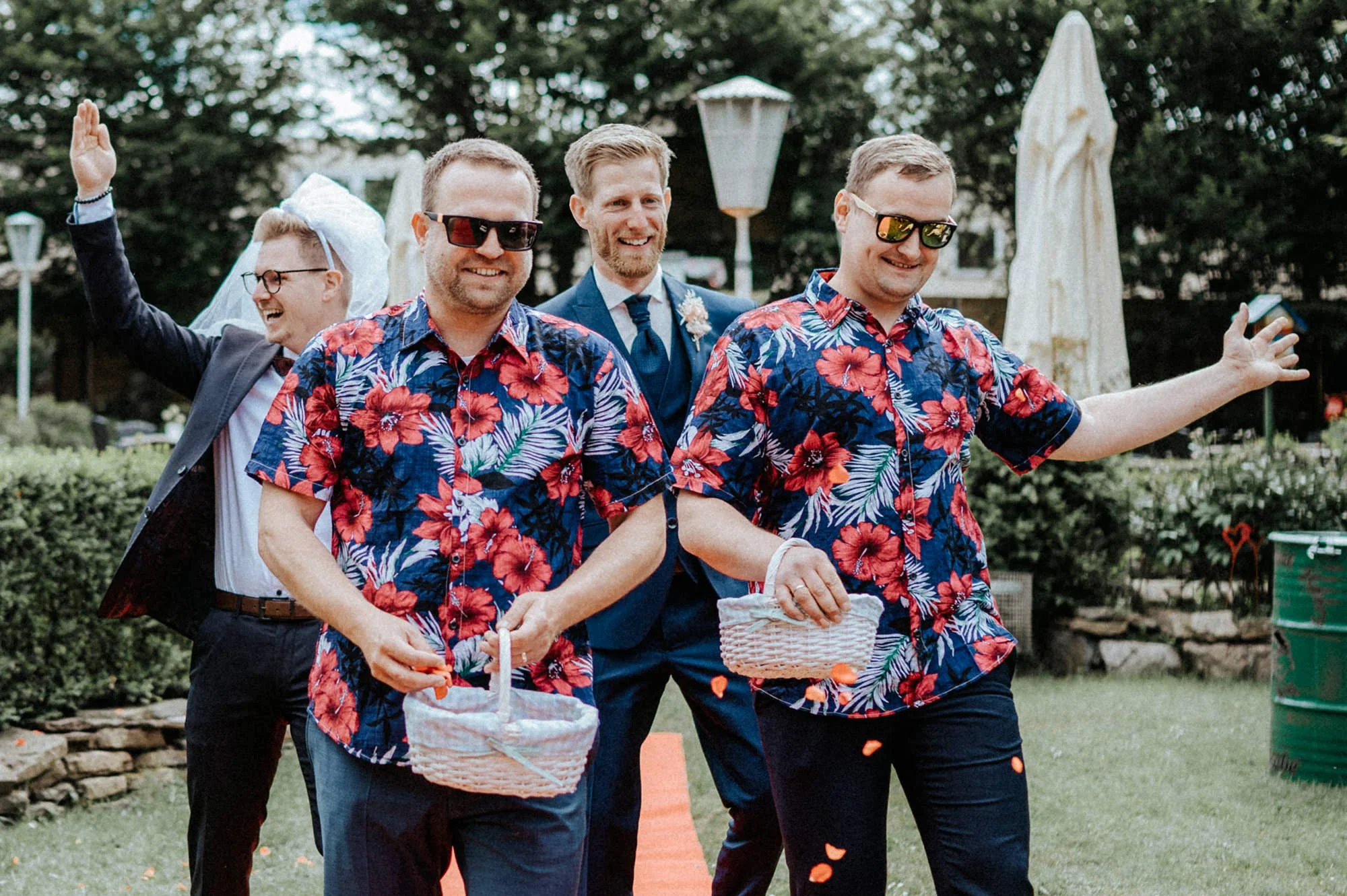 Gruppen von Männern bei einer Hochzeit, einige tragen bunte Hawaiihemden, freuen sich und haben Spaß im Garten