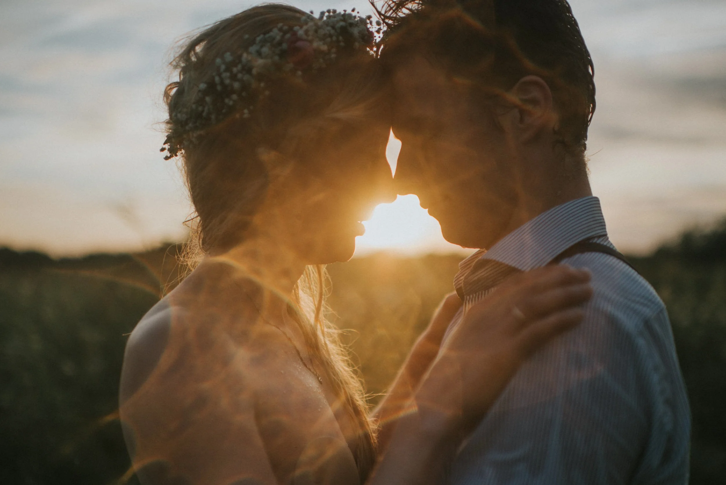 Ein Paar küsst sich bei Sonnenuntergang im Freien, Silhouette sichtbar, Frühlings- oder Sommerszene.