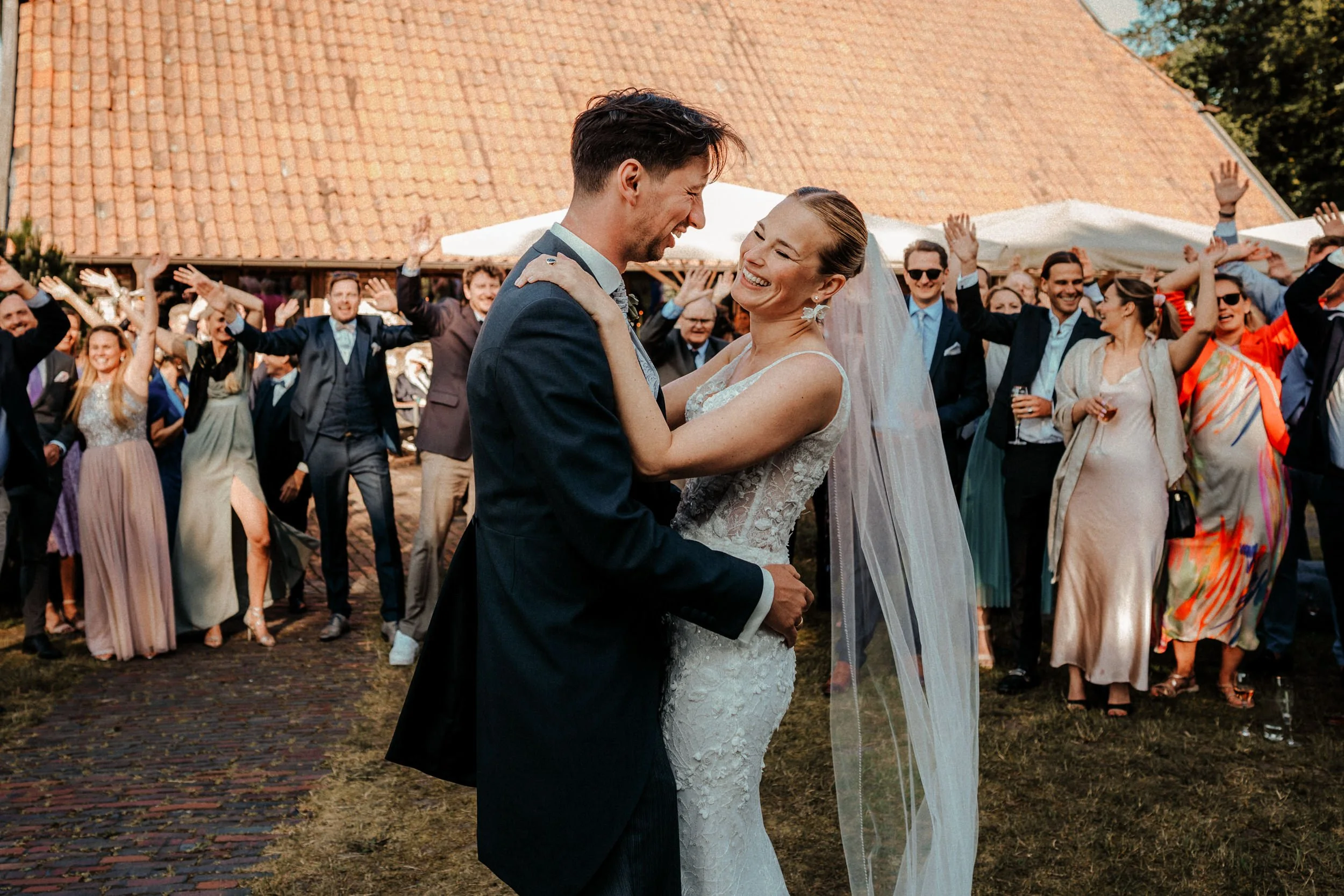 Ein Paar tanzt bei einer Hochzeit im Freien, umgeben von Gästen, die zuschauen und feiern.
