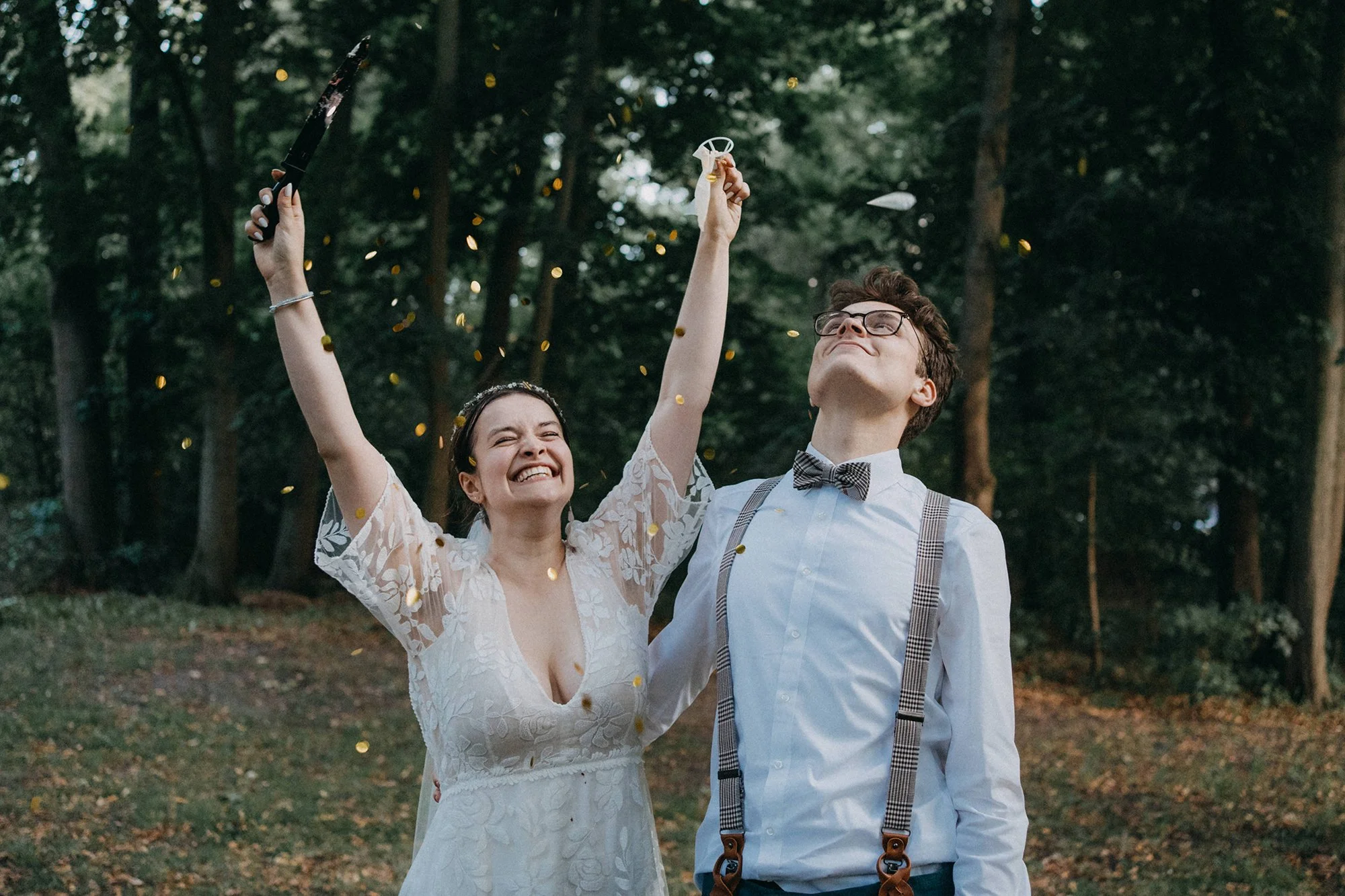 Ein glückliches Paar bei einer Hochzeit im Wald, das mit Konfetti und Hochzeitszubehör feiert.