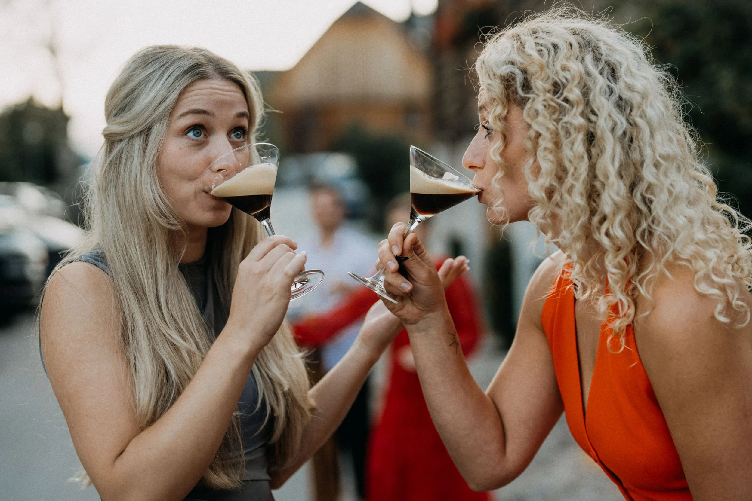 Zwei Frauen trinken Rotwein beim Anstoßen im Freien.