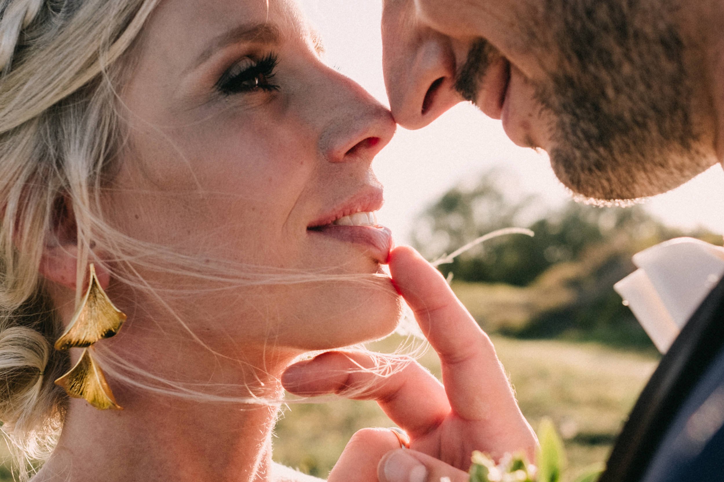 Ein Mann und eine Frau stehen sich nahe und berühren sich mit den Nasen, wobei sie einander anlächelnd in die Augen schauen.