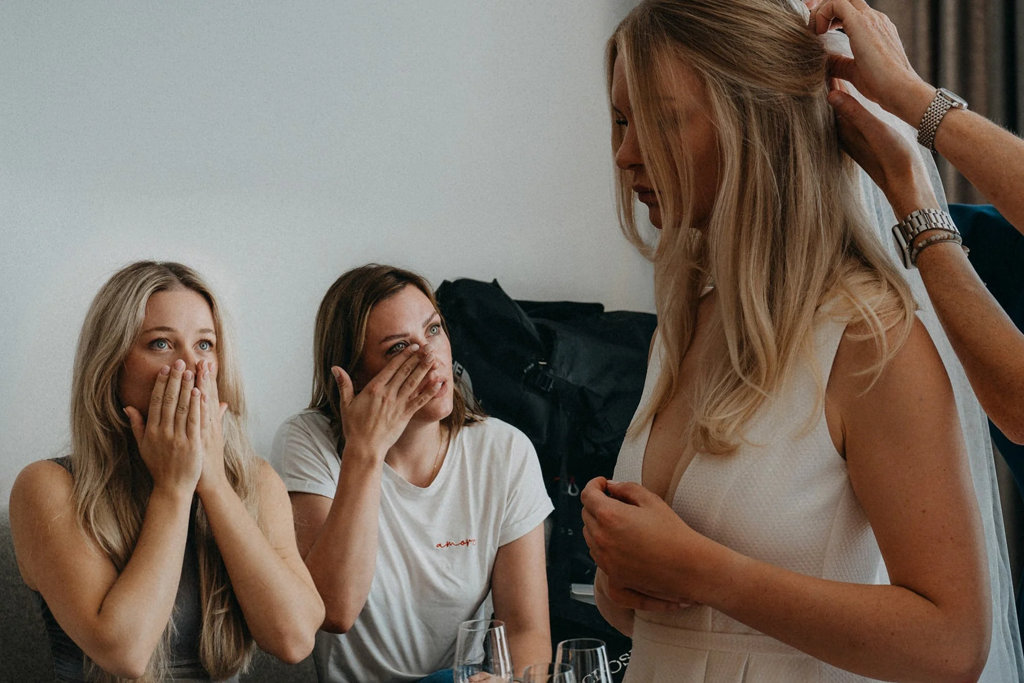 Drei Frauen reagieren erstaunt auf eine andere stehende Frau, die mit ihr spricht, während sie bei einer Zusammenkunft oder Feier sitzen.
