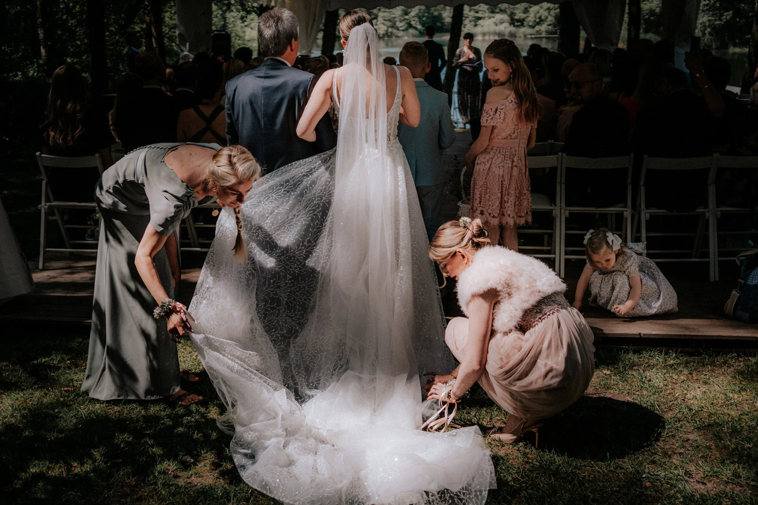 Hochzeit im Freien mit Braut, Bräutigam und Gästen, die Blumen auf dem Boden legen.