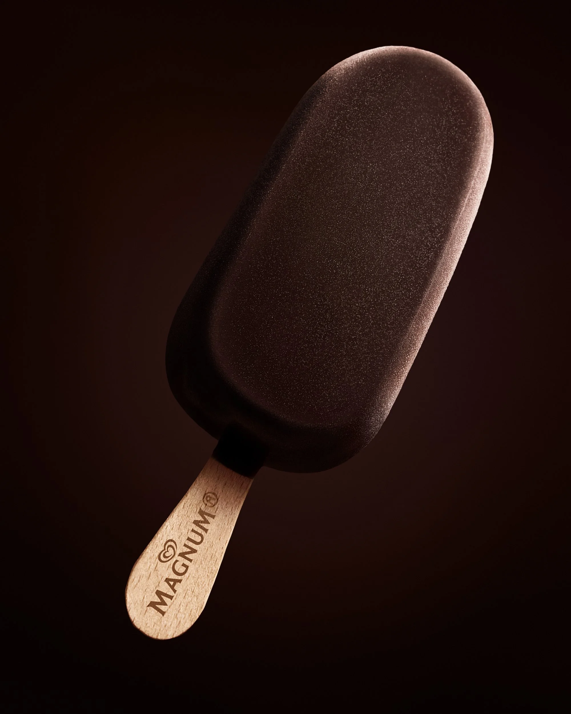 A chocolate coated popsicle with a wooden stick and a cautionary message printed on it, set against a dark background.