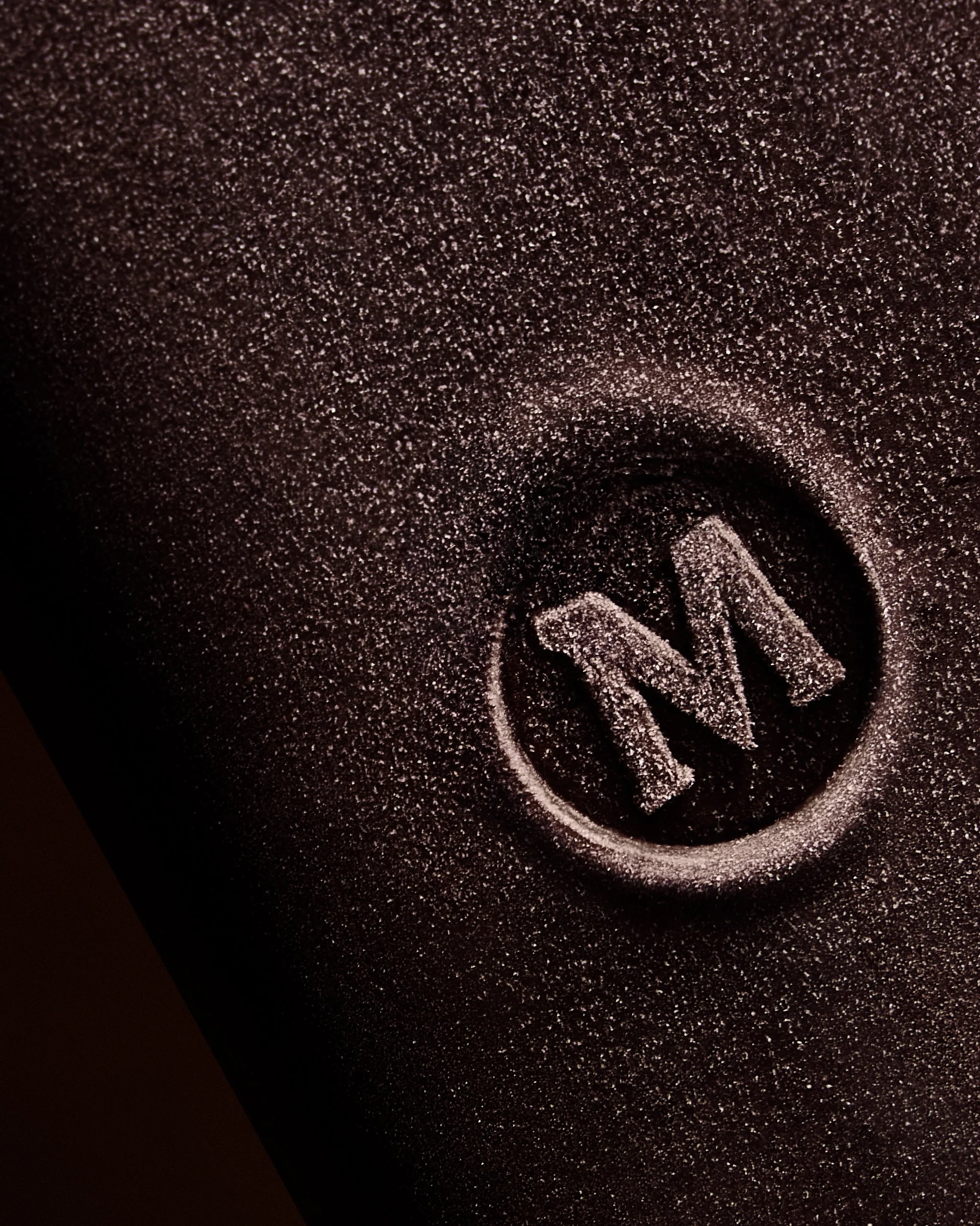 Close-up of a black textured surface with a single white chalk drawing of a circled atom symbol.