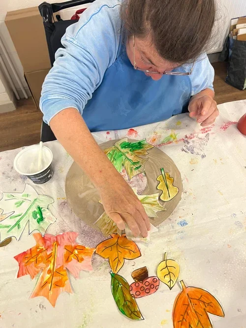 A lady creating a picture of with leaves and paint