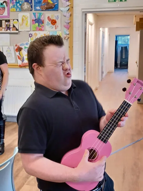 A man playing a pink guitar