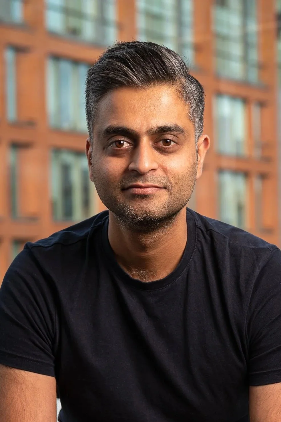 Bilde av Jiten Vara som sitter på en krakk og smiler mot kamera. Foto.