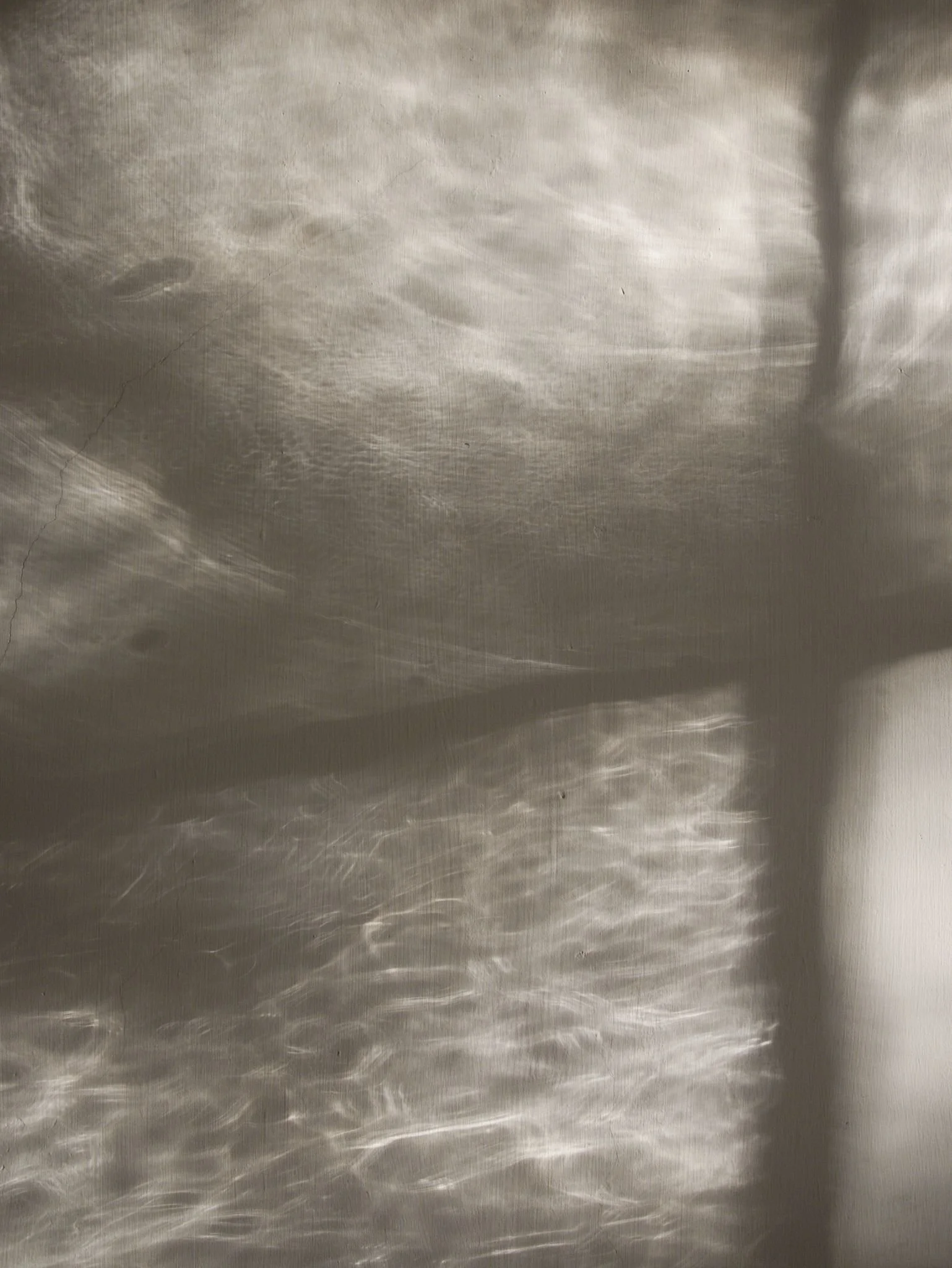 Caustic window reflections cast over a light grey wall.