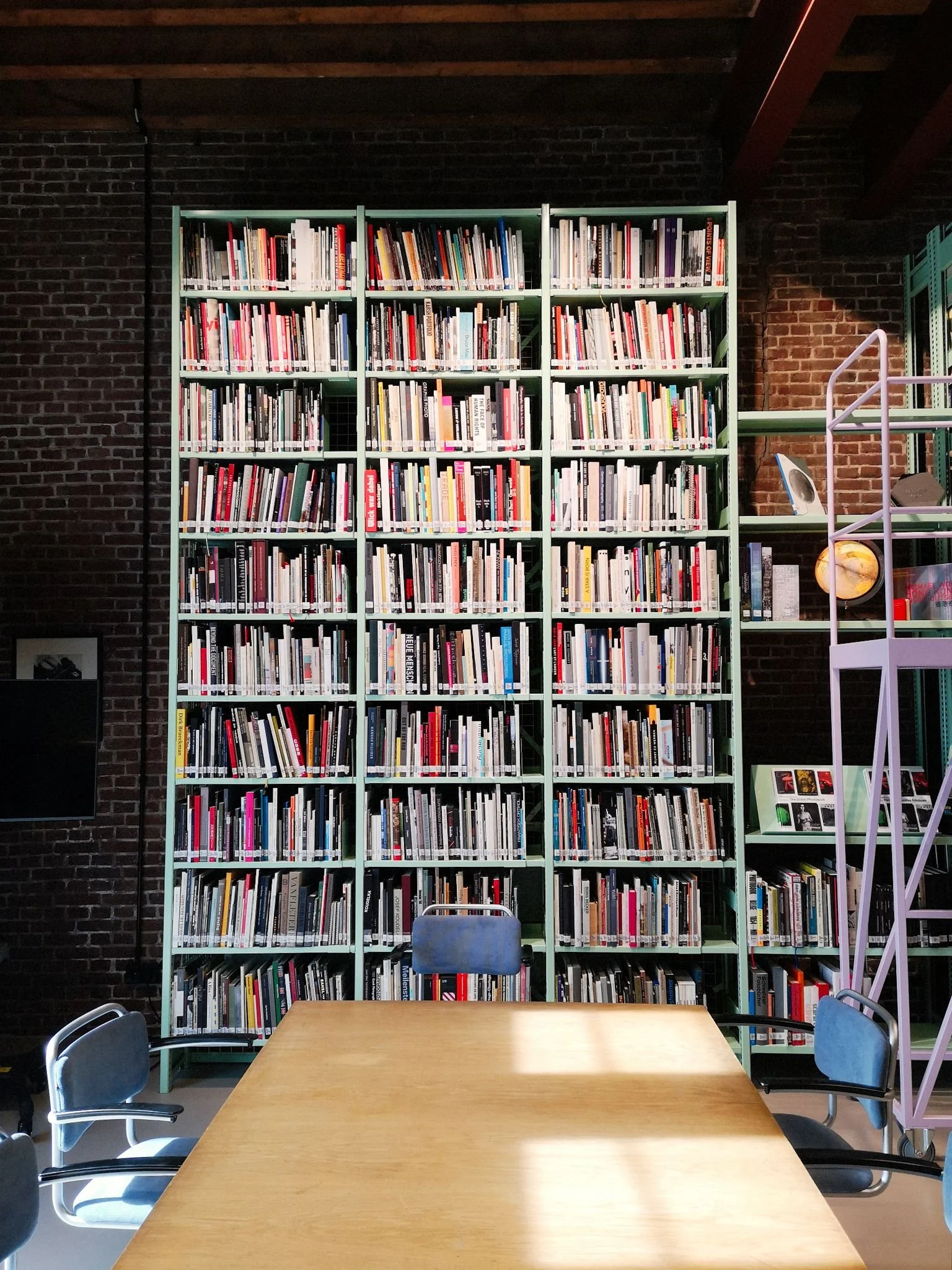 A small part of the Nederlands Fotomuseum featuring a tall bookcase and table.