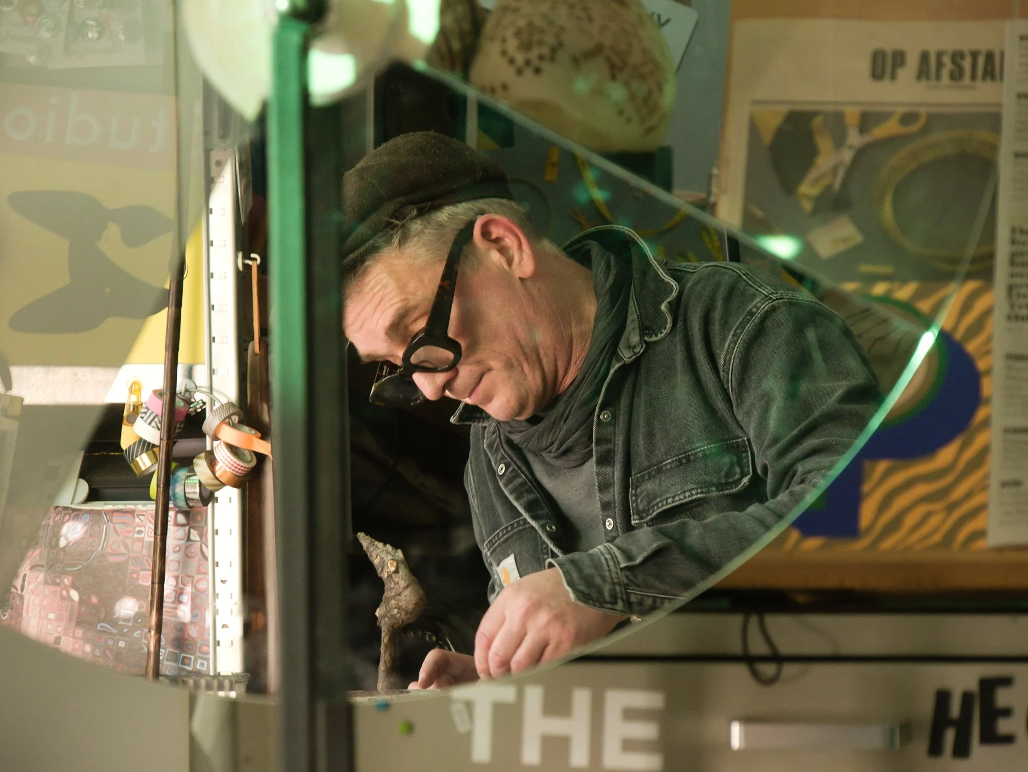 Designer Martin Pyper working in his studio reflected in a triangular mirror.