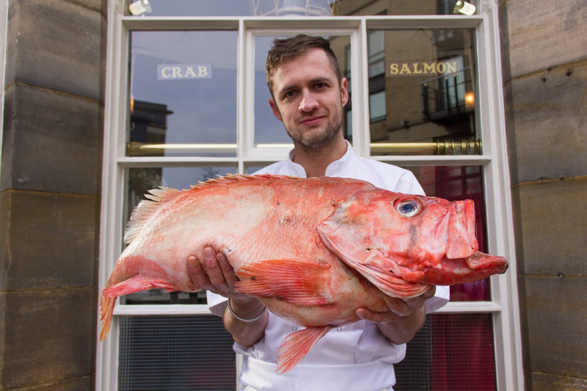 A chef holding a big red fish outside the Drum and Monkey seafood restaurant in Harrogate.