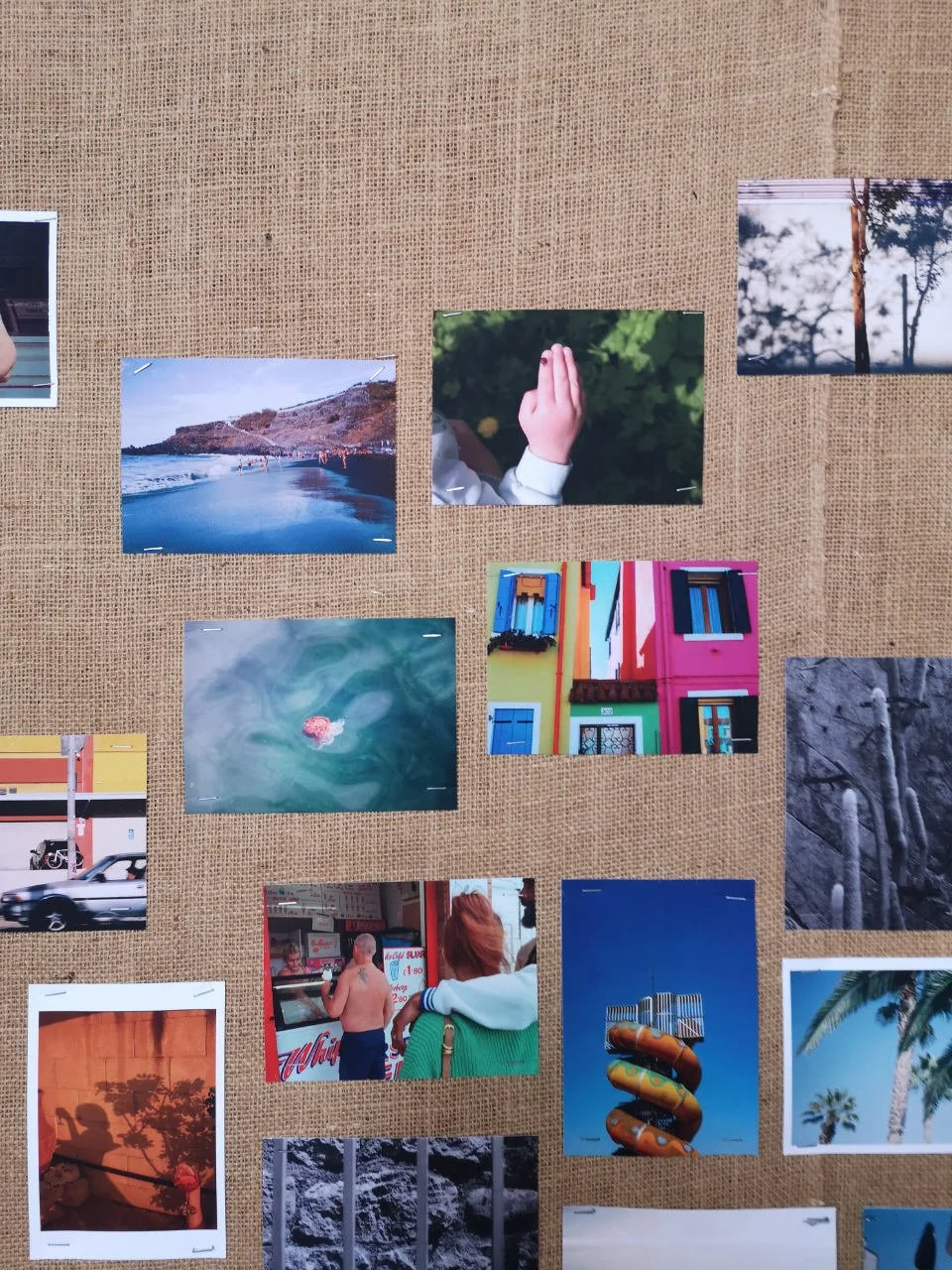 Lots of postcard sized prints featuring holidays in some form pinned to a sack cloth board.