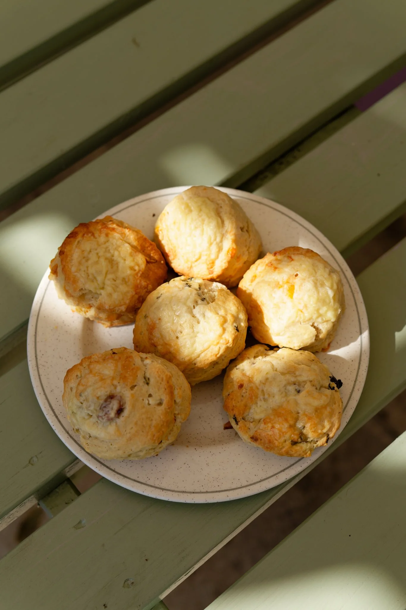 Six scones sitting on a plate in the dappled autumn sunshine.