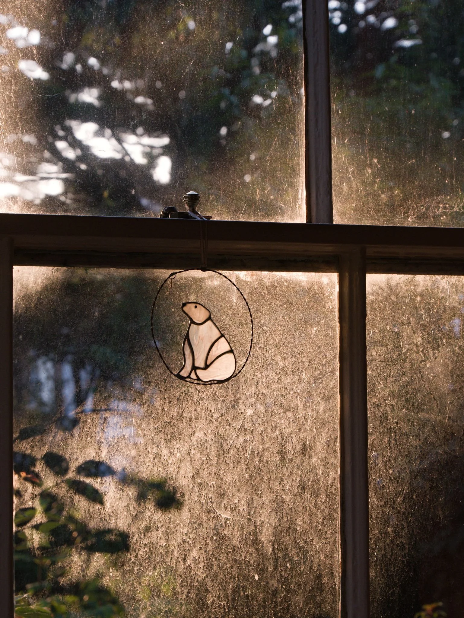 Looking directly out of a sunlit window with a polar bear glass ornament hanging on the frame.