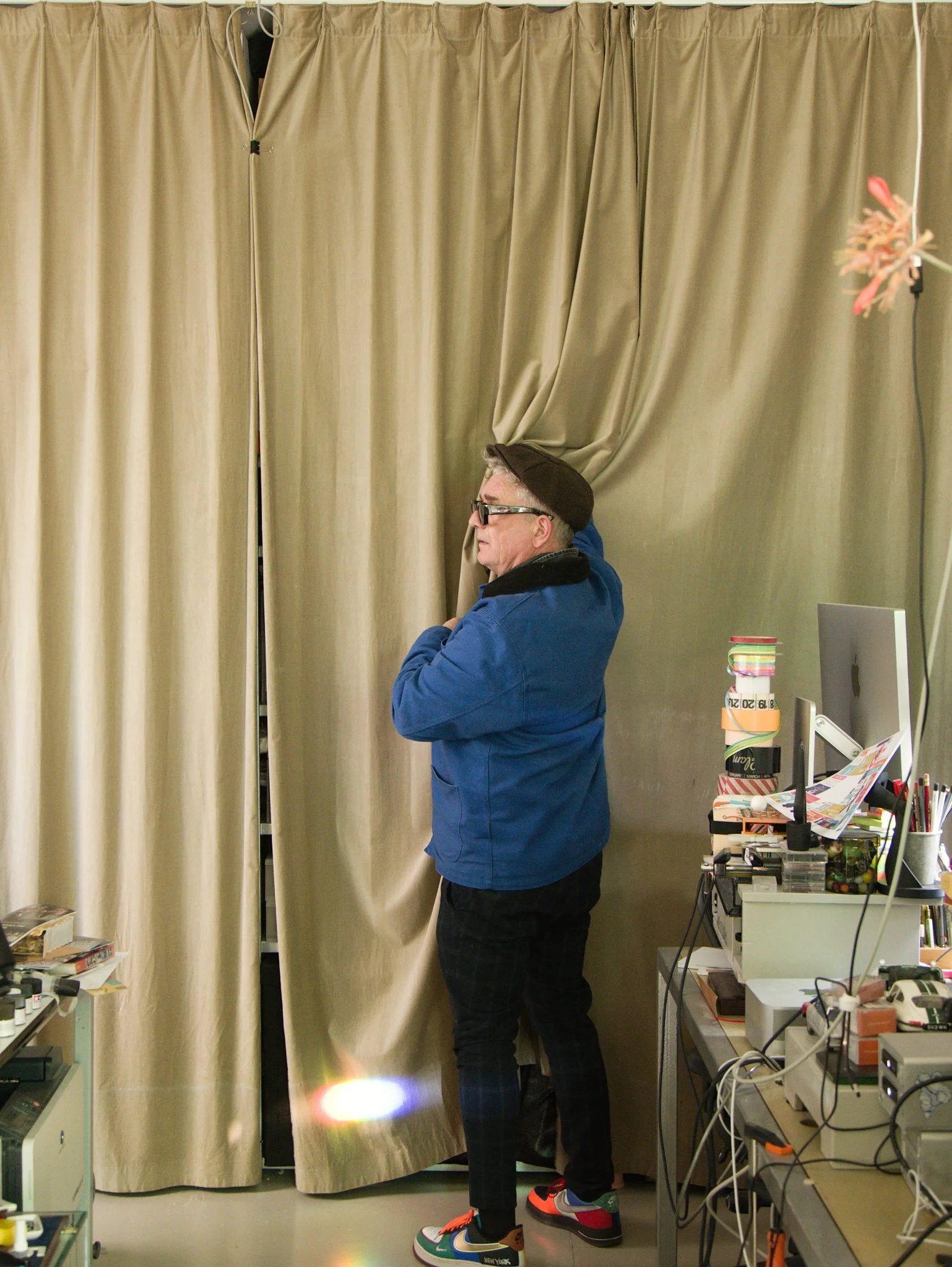 Designer Martin Pyper looking for something behind a big curtain in his studio in Amsterdam.