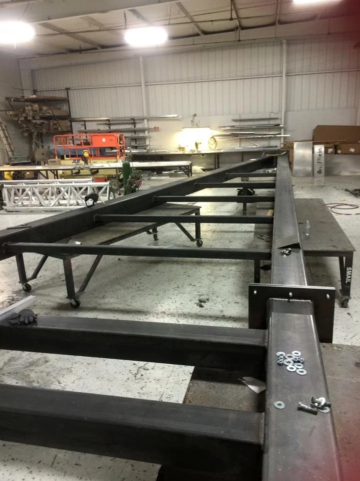 Large fabricated metal frame structure on wheels inside the UFB shop