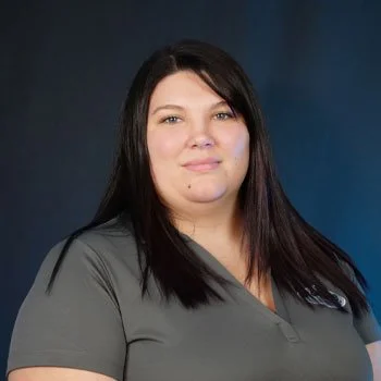 A woman standing in front of a blue wall with white text and a green and blue logo.