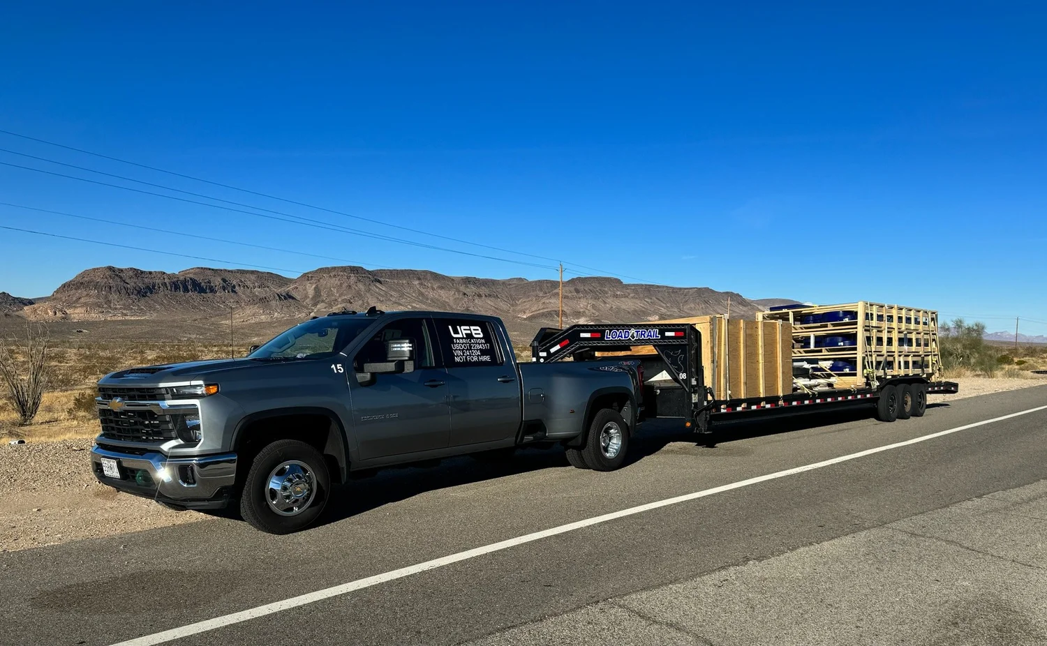 UFB truck towing a loaded flatbed trailer on a desert highway