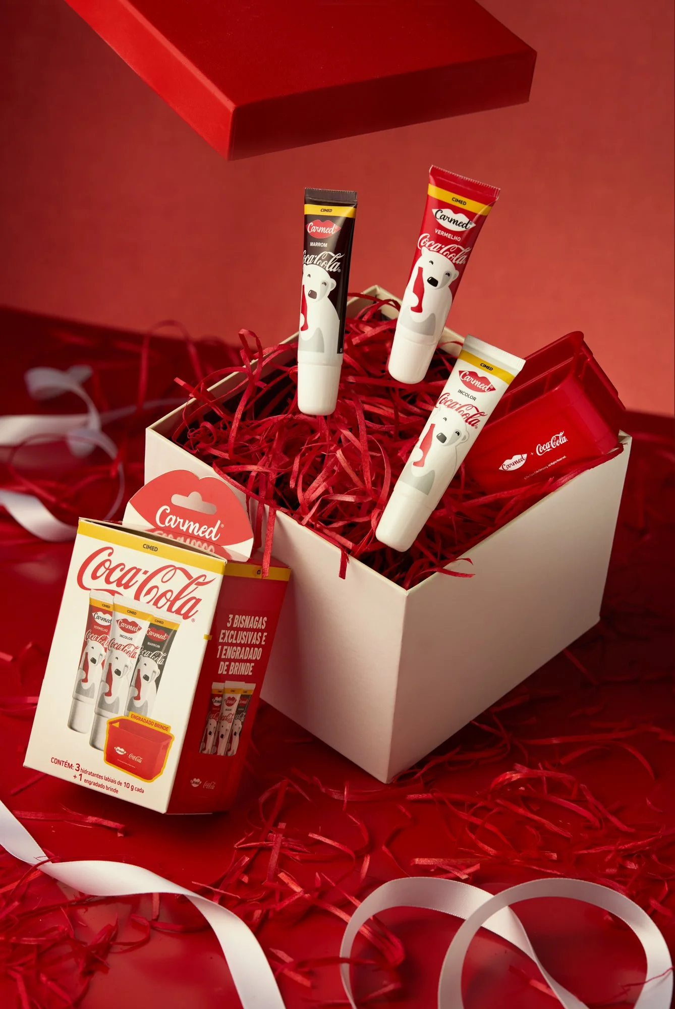 Caixa com produtos de brigadeiro de Coca-Cola em embalagens decoradas com um urso branco. Caixa decorada com papéis decorativos vermelhos e brancos.