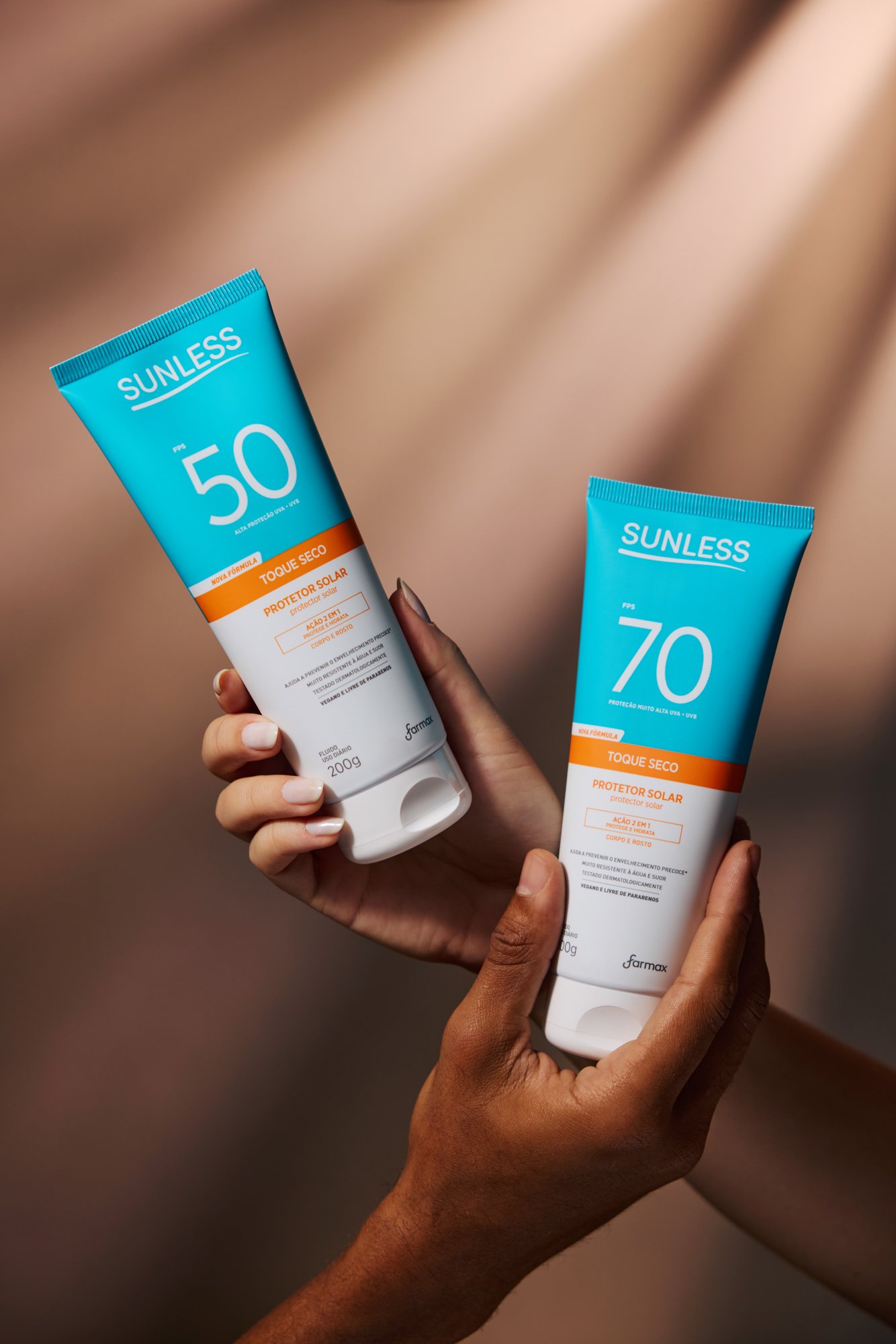 Duas mãos segurando tubos de protetor solar com proteção solar 50 e 70.
