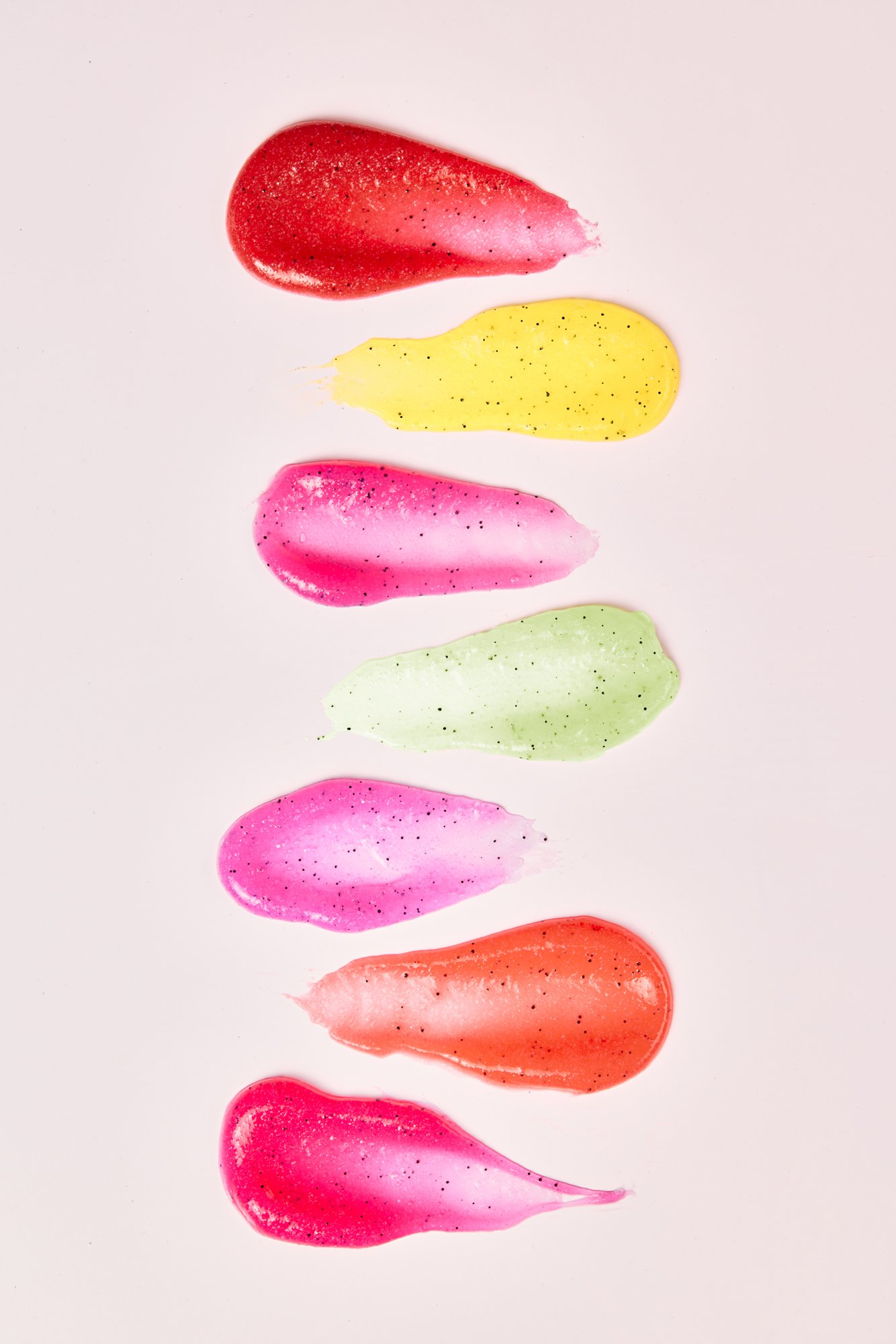 Seis manchas de óleo de cores variadas, incluindo vermelho, amarelo, rosa, verde, roxo e laranja, sobre fundo branco.