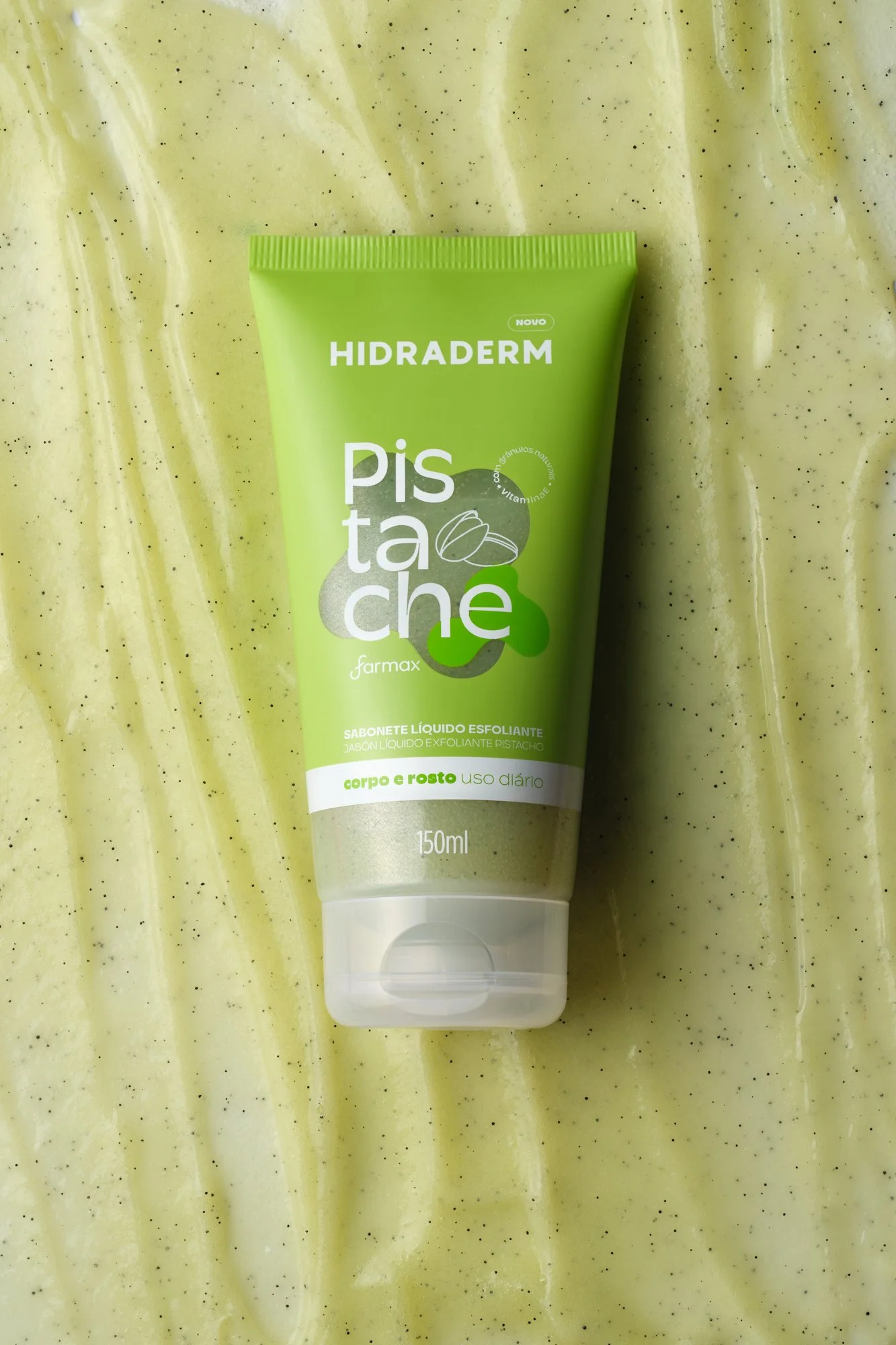 Produto de sabonete líquido esfoliante de cor verde, com embalagem de 150ml, marca Hidraderm, com ingredientes de farinha de pistache para uso diário no corpo e rosto.