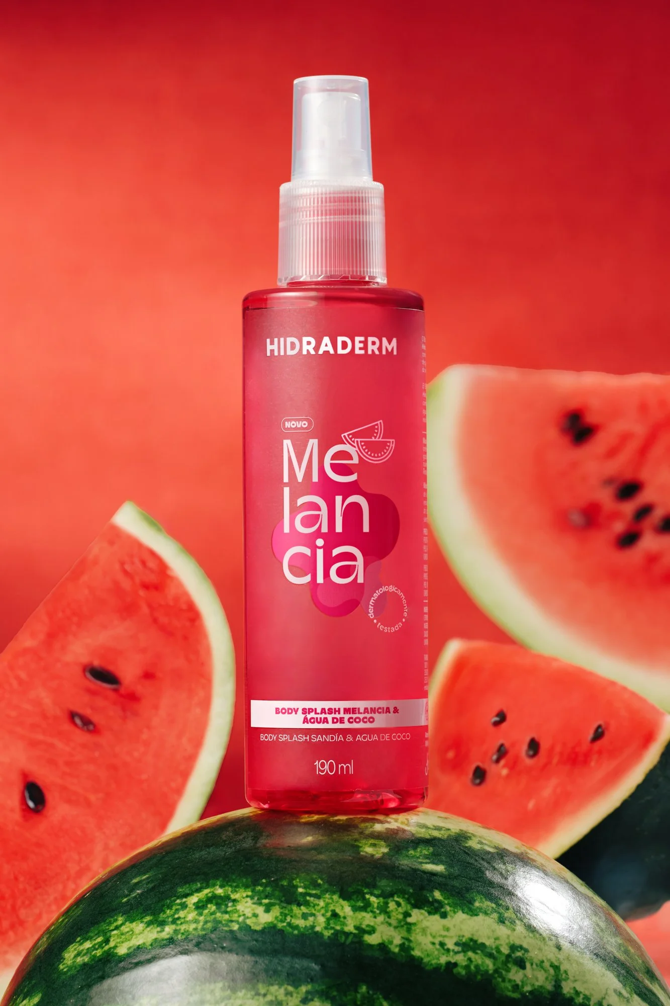 Spray corporal de fragrância Melancia e Água de Coco apoiado em uma melancia em um fundo de fatias de melancia.