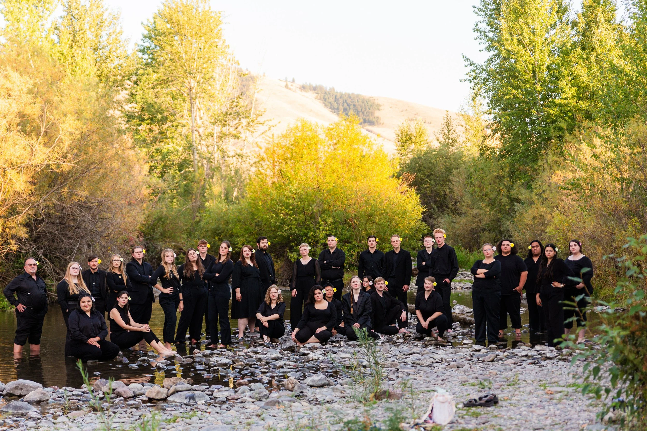 All members of 'Aiga standing in stream in various poses with a fall background of trees and hills