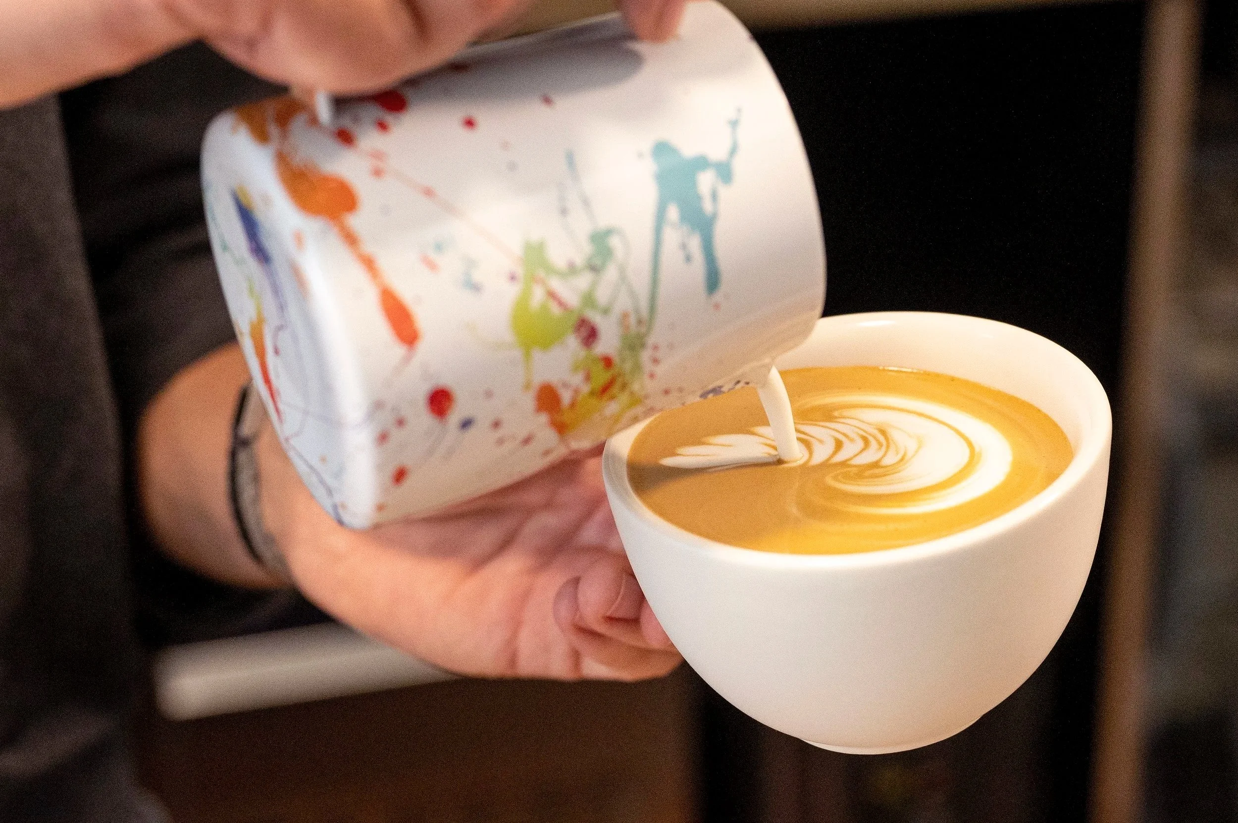 Ein Barista gießt Latte Art in eine Tasse und zeichnet einen Schwan auf einem cremigem Espresso.