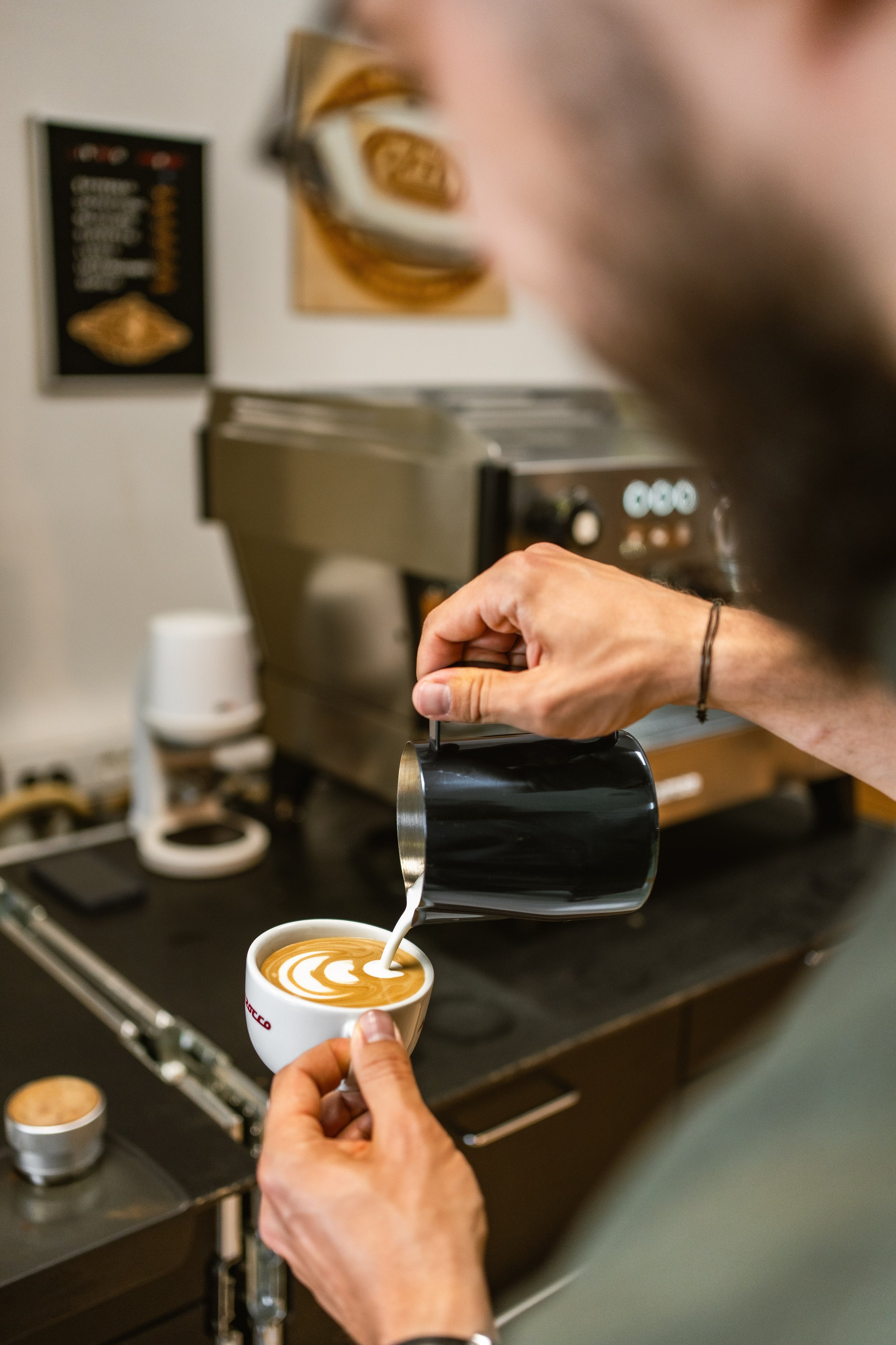 Barista gießt Latte Art in eine Tasse zum fertigen Cappuccino.