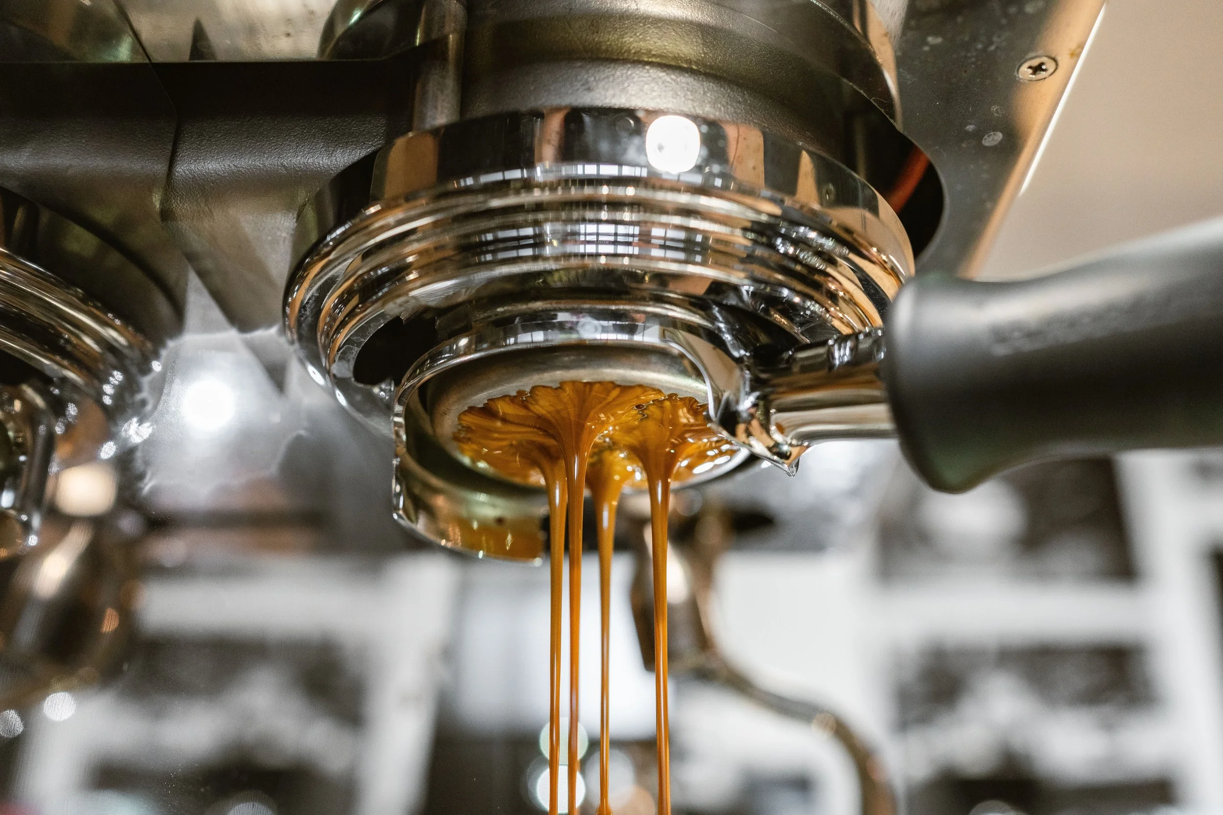 Nahaufnahme von einer Espressomaschine, die frisch gebrühten Espresso in eine Tasse aufgießt.