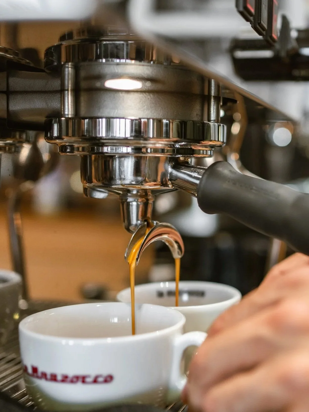 Ein Espressomaschine der Marke La Marzocco brüht Espresso in zwei weiße Tassen.