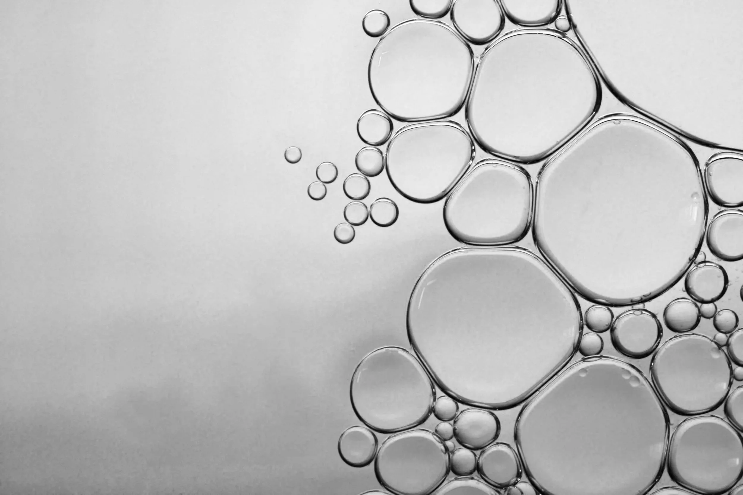 Bubbles or oil droplets dispersed on a smooth surface, with a gradient background.